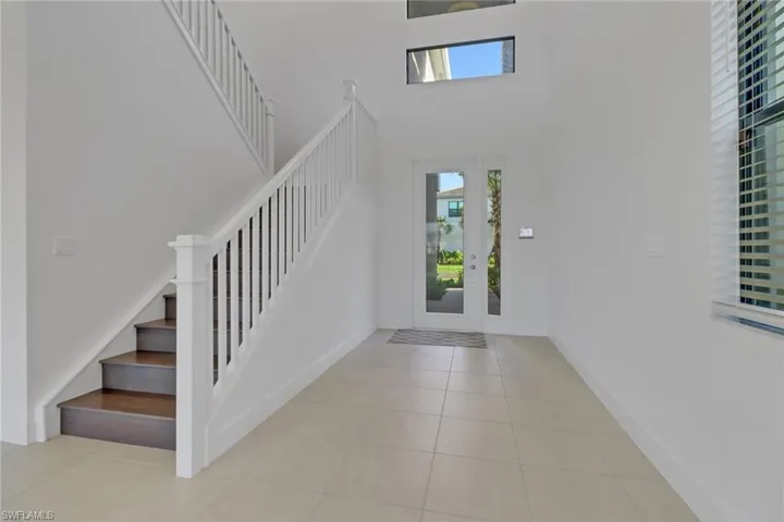 Foyer with stairway, plenty of natural light, tile patterned floors, and a towering ceiling