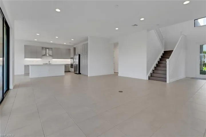 Unfurnished living room featuring stairway, a sink, and recessed lighting