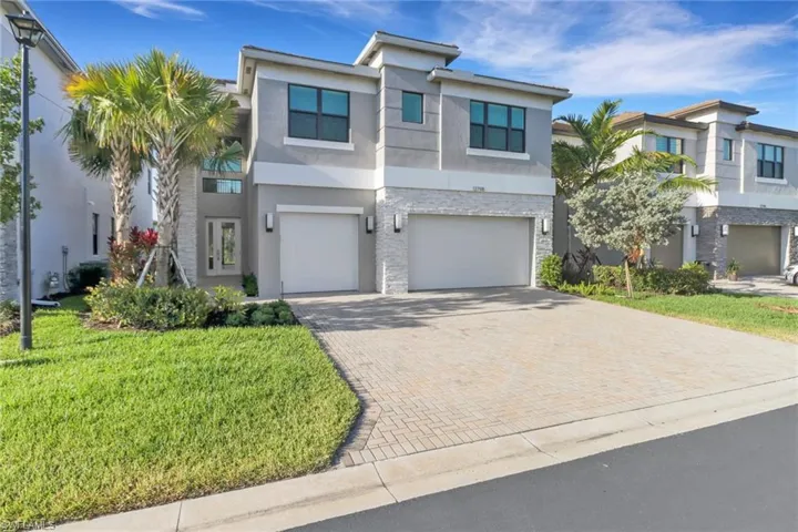 View of front of house featuring a garage, stucco siding, decorative driveway, and a front yard
