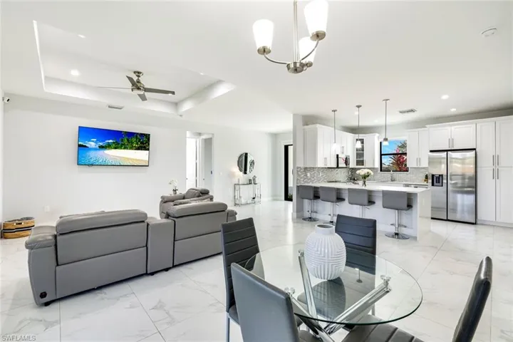 Dining space with a ceiling fan, light marble finish flooring, and suspended lighting