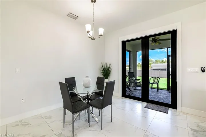 Dining space featuring hanging lights and light marble finish flooring