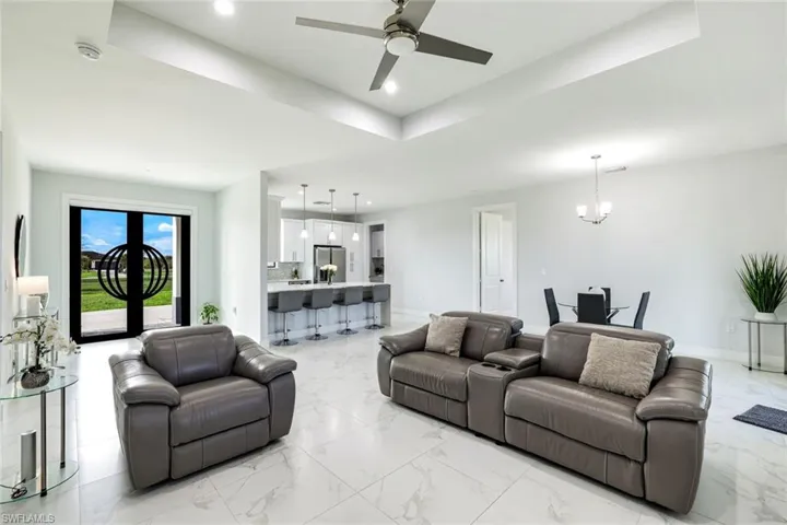 Living area with a chandelier, ceiling fan, and a raised ceiling
