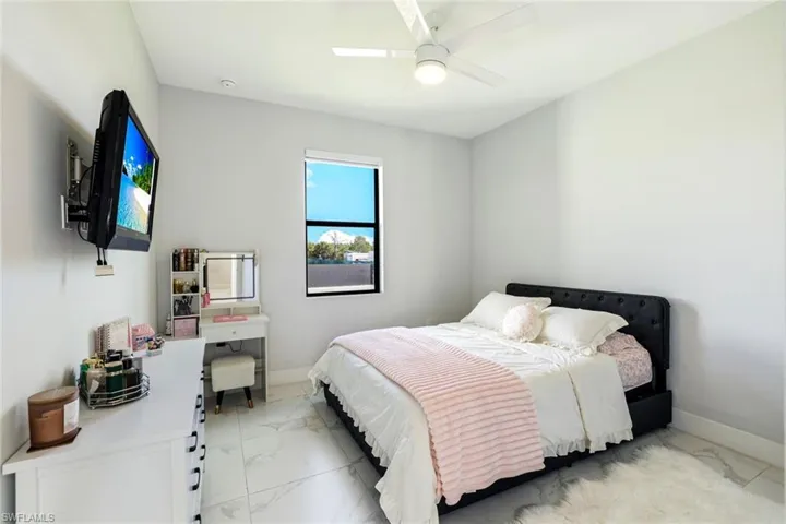 Bedroom featuring light marble finish floors and ceiling fan