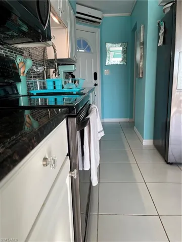 Kitchen with an AC split unit,  range, light tile patterned floors, decorative backsplash, and baseboards