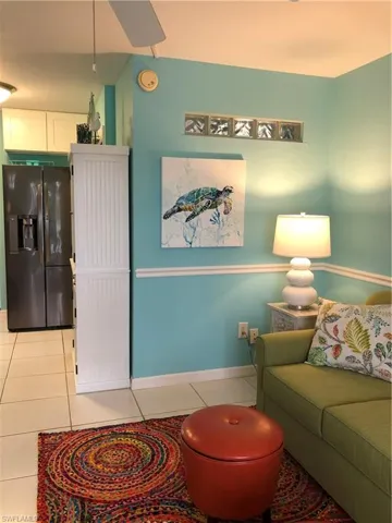 Living area with chair rail and light tile patterned flooring, and vaulted ceiling
