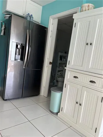 Kitchen featuring white cabinetry, refrigerator, and light tile patterned floors