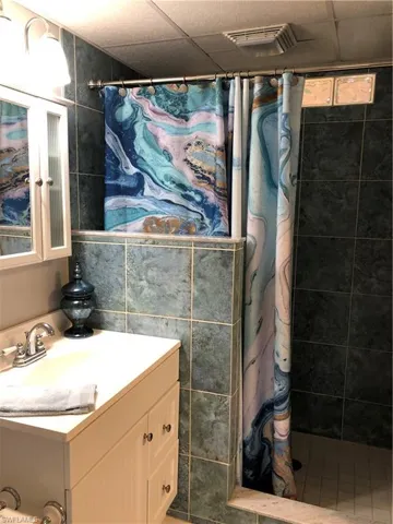 Full bath featuring vanity, and tiled shower