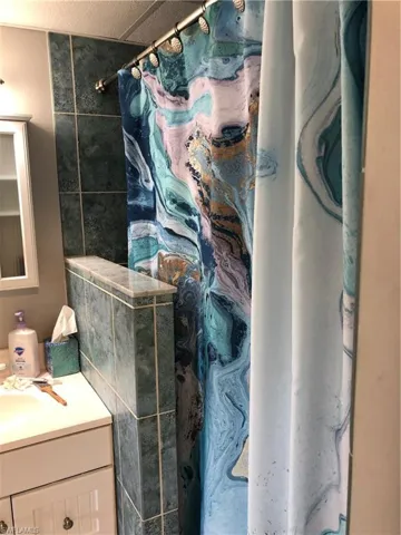 Bathroom featuring curtained walk in shower and vanity