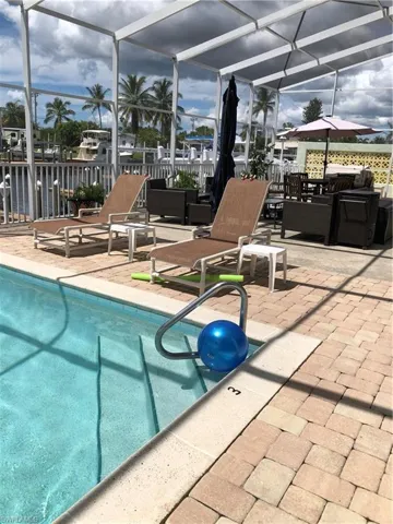Outdoor pool featuring screened enclosure and a patio area