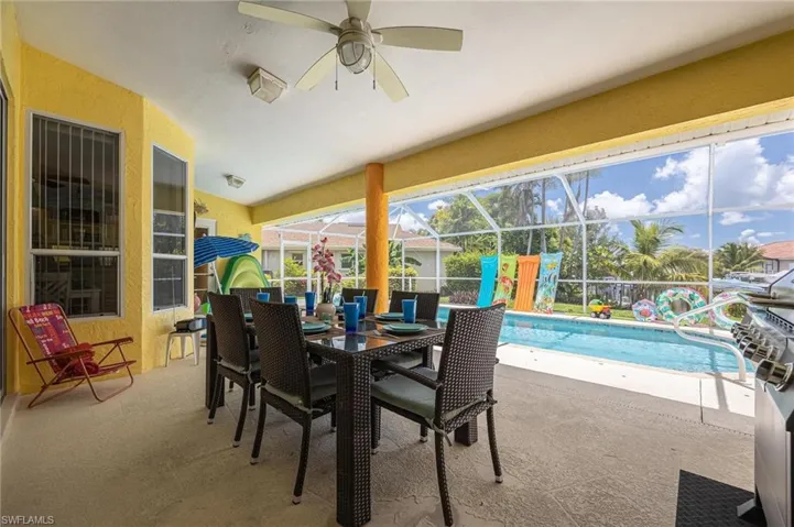 View of patio with a ceiling fan and glass enclosure