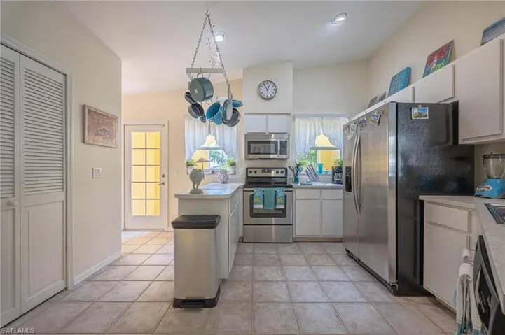 Kitchen with stainless steel appliances, light countertops, white cabinetry, and light tile patterned floors