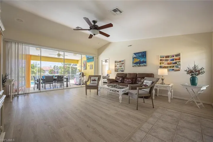 Living room with ceiling fan, lofted ceiling, wood finished floors, and baseboards