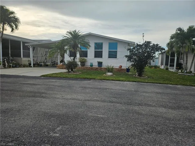 View of front of property featuring a front lawn and a carport