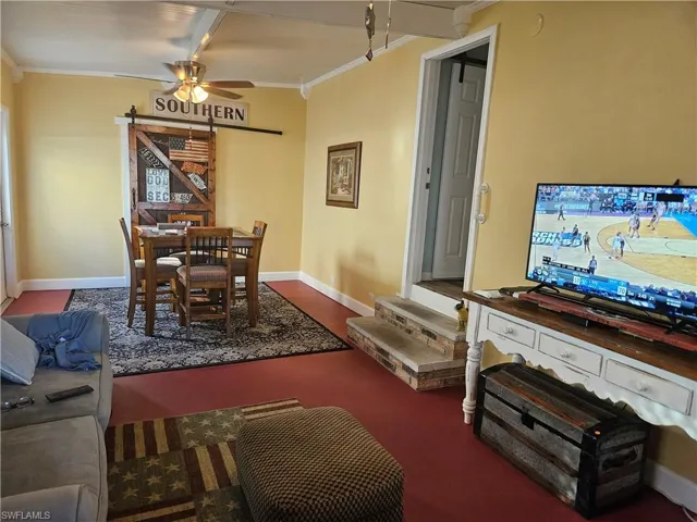 Living area with baseboards, crown molding, and a ceiling fan