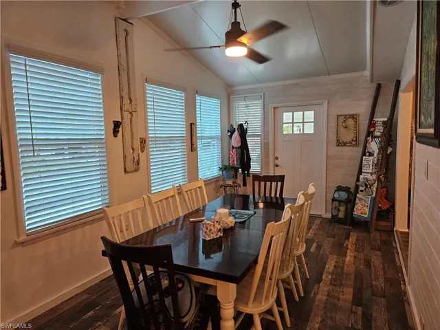 Dining space with dark wood-type flooring, ornamental molding, ceiling fan, and vaulted ceiling