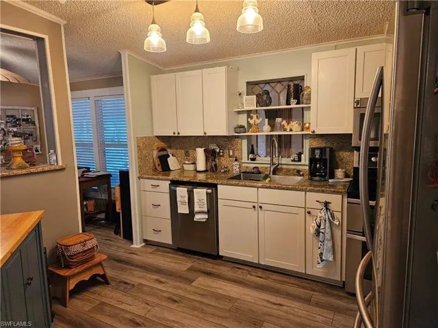 Kitchen featuring sink, white cabinetry, stainless steel appliances, dark hardwood / wood-style floors, and decorative light fixtures