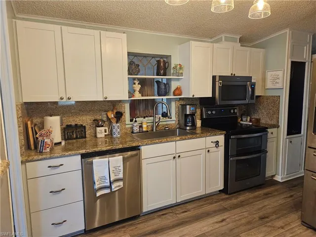 Kitchen featuring a sink, white cabinets, dark wood finished floors, and stainless steel appliances