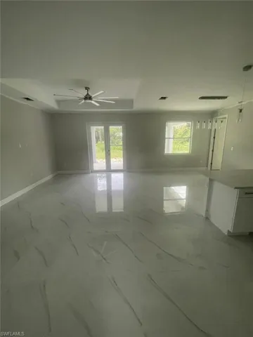 Tiled empty room featuring ceiling fan and a wealth of natural light