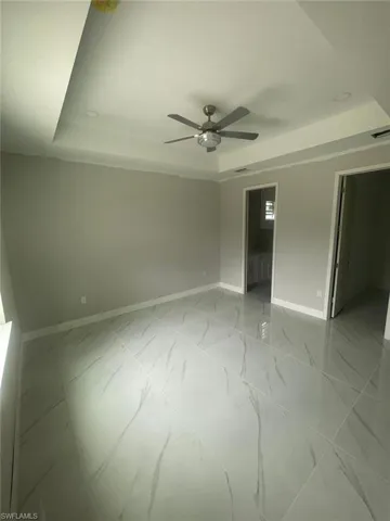 Tiled spare room with ceiling fan and a raised ceiling