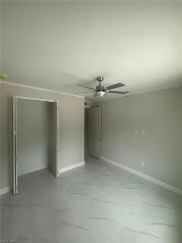 Unfurnished bedroom with ceiling fan and light tile flooring