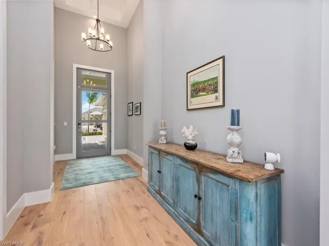Entrance foyer featuring an inviting chandelier, light hardwood / wood-style flooring, and a towering ceiling