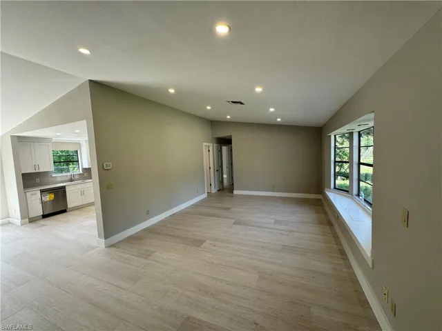 Spare room featuring sink, lofted ceiling, and light wood-type flooring