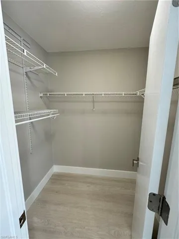 Walk in closet with light hardwood / wood-style flooring