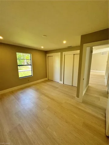 Unfurnished bedroom with two closets and light hardwood / wood-style floors
