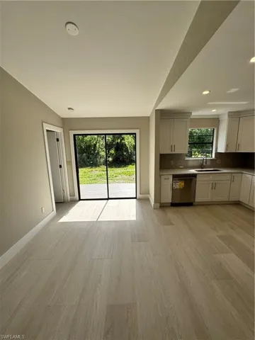 Unfurnished living room with sink and light hardwood / wood-style flooring