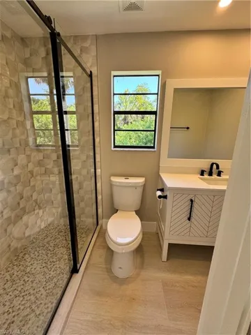 Bathroom with a shower with shower door, toilet, and vanity