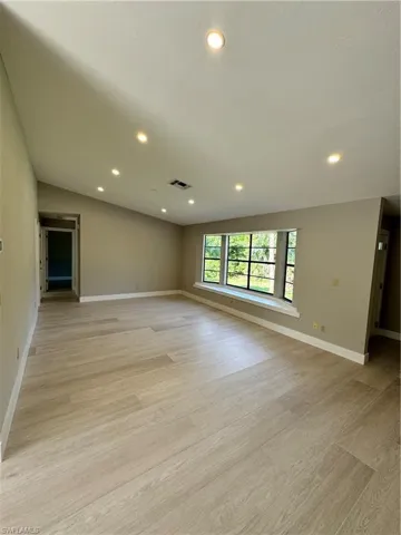 Spare room featuring light hardwood / wood-style flooring and lofted ceiling