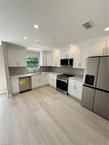 Kitchen with fridge, dishwashing machine, range, backsplash, and sink
