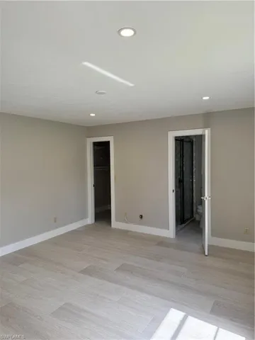 Unfurnished bedroom with light hardwood / wood-style floors and ensuite bath