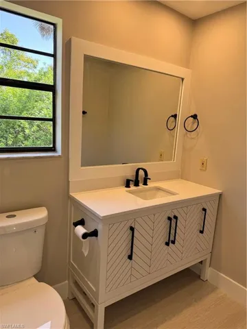 Bathroom featuring oversized vanity, toilet, and wood-type flooring