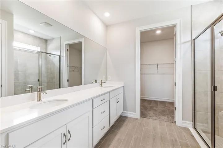 Bathroom with a spacious closet, a stall shower, wood finish floors, and recessed lighting
