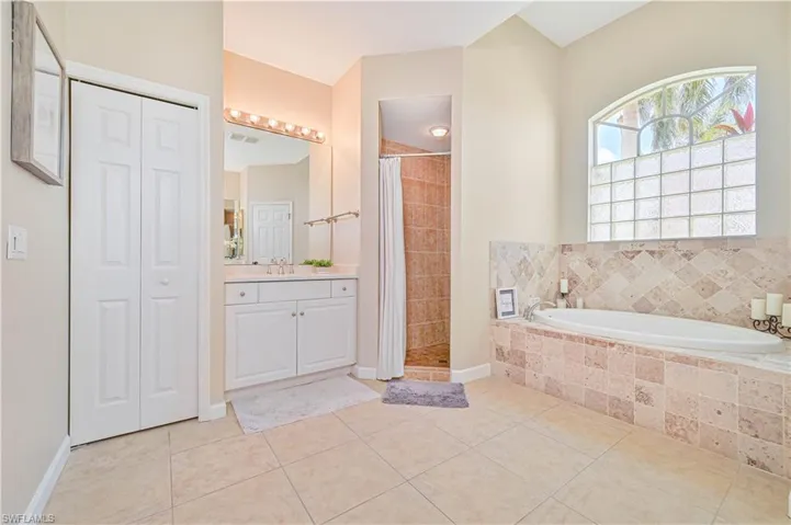Bathroom with a stall shower, vanity, a bath, and a closet