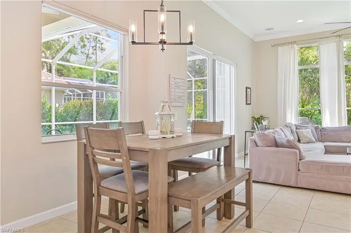 Dining area with crown molding, light tile patterned floors, and hanging lights