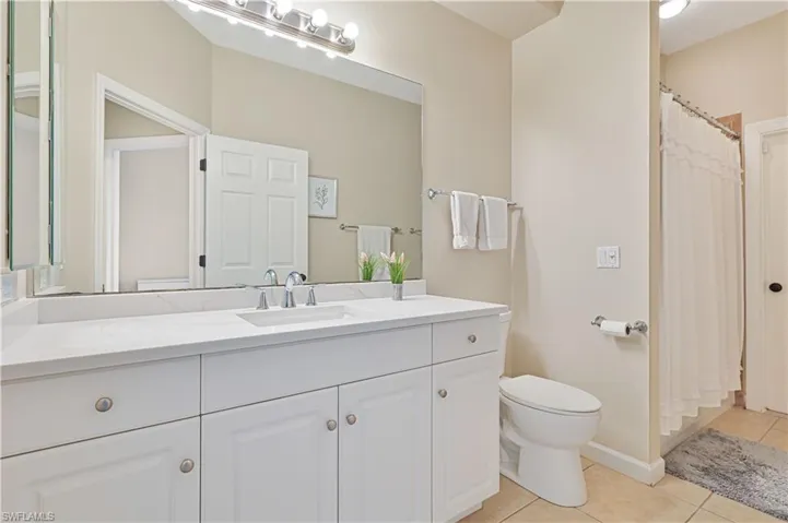 Bathroom featuring light tile patterned floors, vanity, and a shower with shower curtain