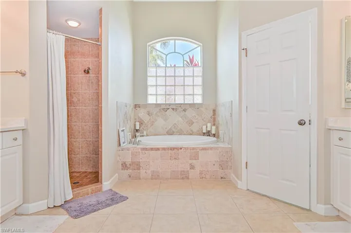 Full bath with vanity, a shower stall, a garden tub, and light tile patterned flooring