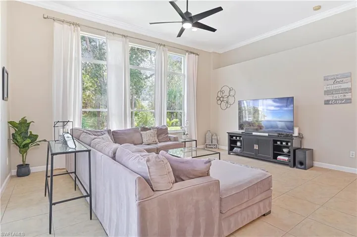 Living room featuring a ceiling fan, light tile patterned flooring, and ornamental molding
