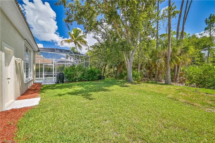 View of green lawn featuring a sunroom and glass enclosure