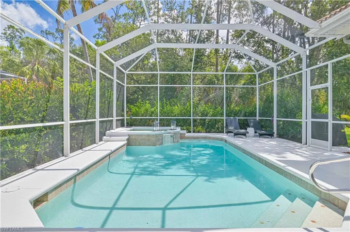 Relaxing pool / spa featuring glass enclosure and a sunroom