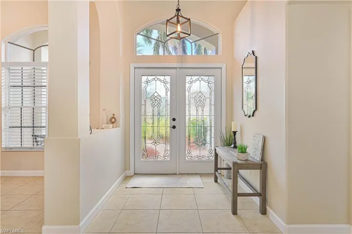 Entryway featuring french doors, light tile patterned flooring, and a high ceiling