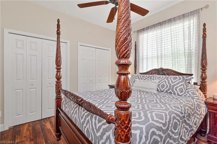 Bedroom featuring two closets, dark wood-type flooring, and a ceiling fan