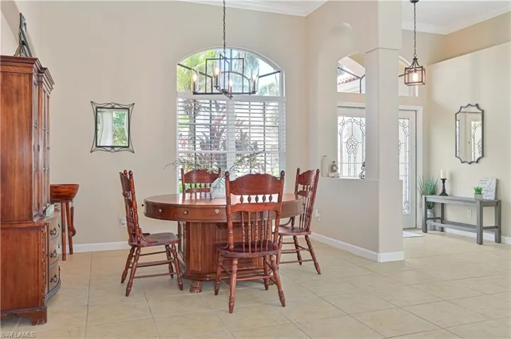 Dining space featuring ornamental molding, a chandelier, and light tile patterned floors
