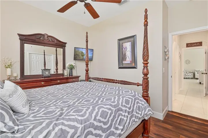 Bedroom featuring dark wood-type flooring, arched walkways, and ceiling fan