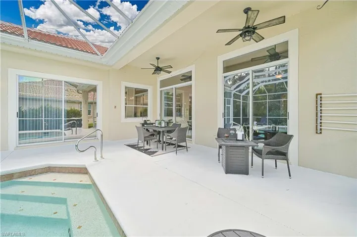 View of patio featuring outdoor dining area, glass enclosure, ceiling fan, and a sunroom