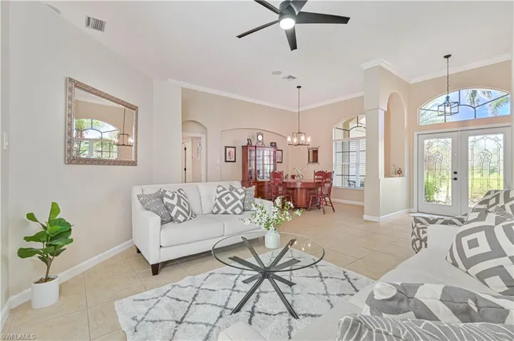Living room with french doors, a ceiling fan, light tile patterned floors, suspended lighting, and crown molding