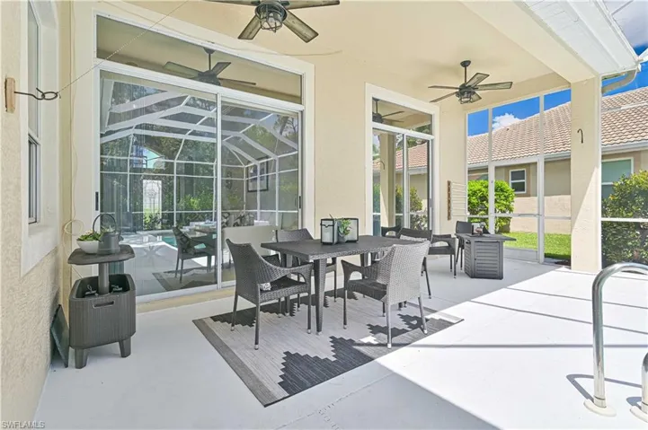 View of patio featuring glass enclosure, outdoor dining space, and a ceiling fan