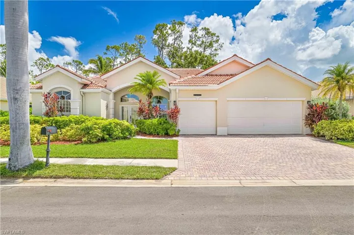 Mediterranean / spanish-style house featuring stucco siding, a tiled roof, decorative driveway, a garage, and a front lawn